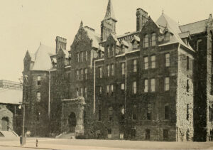 Black and white photo of a large brick building with steeples.