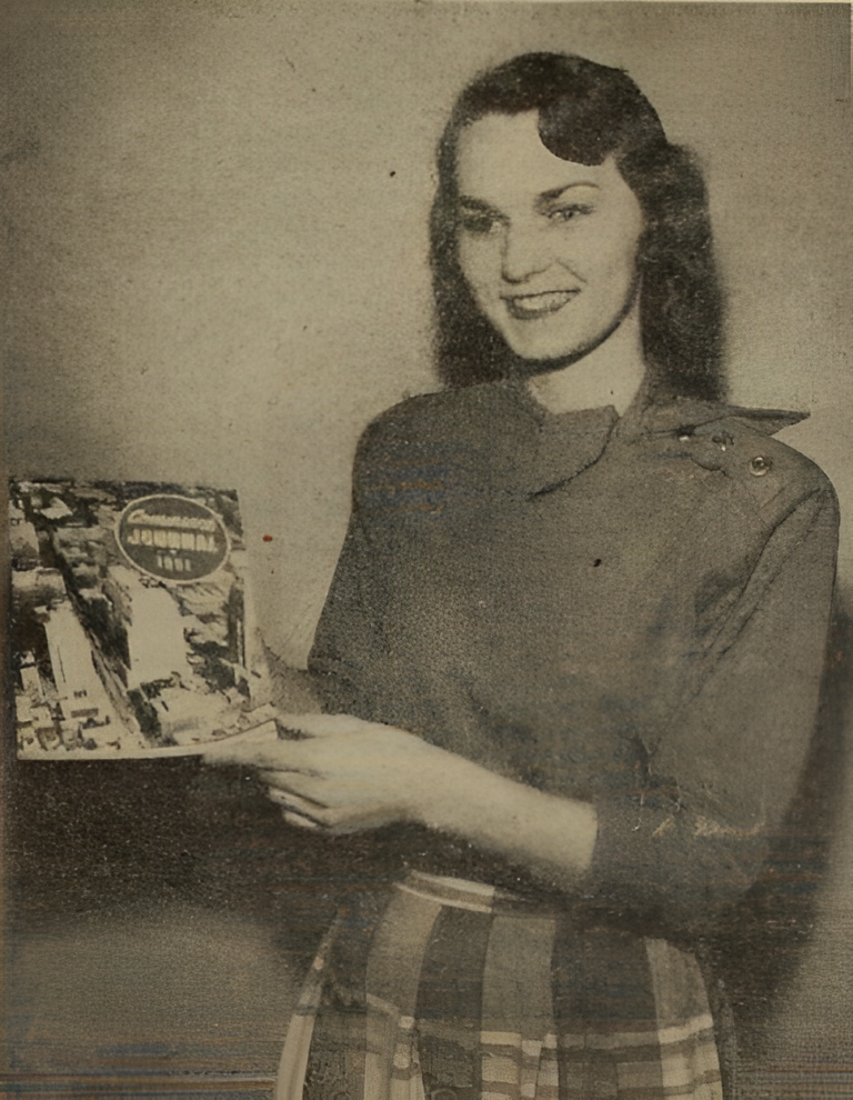 Black and white photo of a women holding a journal that reads The Commerce Journal 1951.