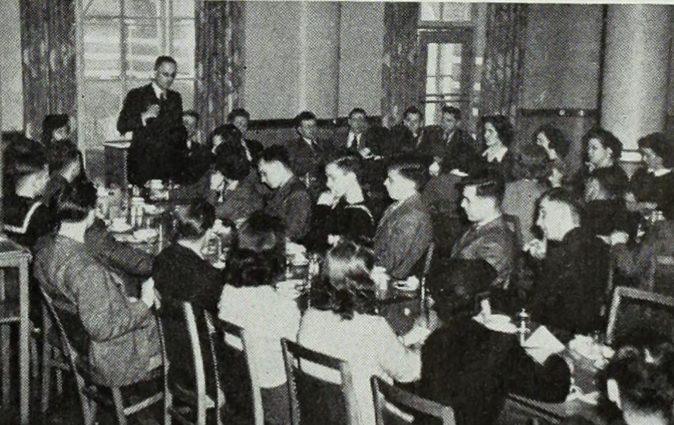 Black and White photograph of Commerce Club members sitting at tables during meeting, 1944
