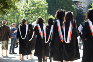 Group of people from the back wearing convocation regalia.