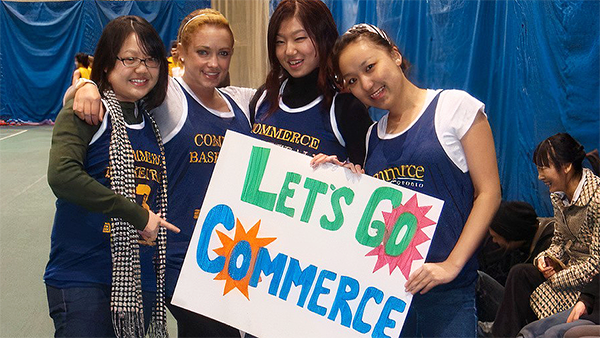 Students holding a Let's Go Commerce sign at a game