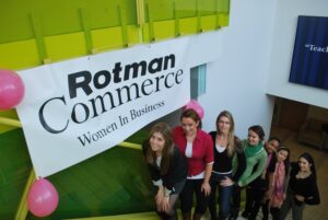 A group of women standing below a large banner that reads ‘Rotman Commerce Women In Business’.