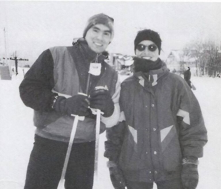 Black and white photo of two people smiling in ski gear.