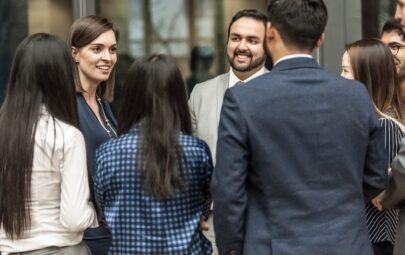 A group of people in suits laughing and talking with one another.