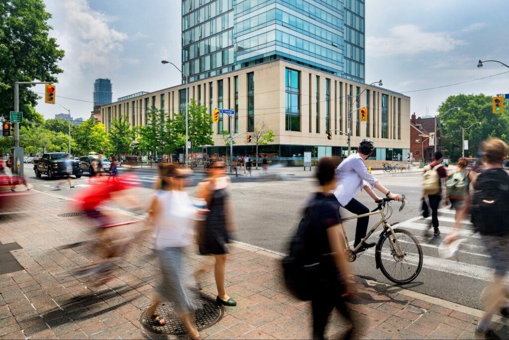 An intersection on St. George Street with many pedestrians in the foreground and a tall building in the background.