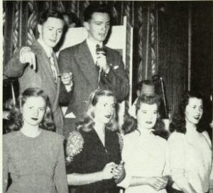 Black and white photo of a group of people in party attire.