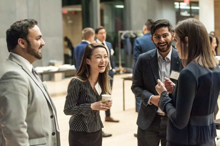 A group of people in suits laughing and talking with one another.