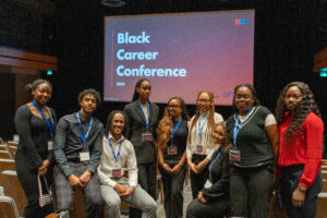 Group of people standing in front a screen that reads Black Career Conference 2023.