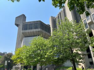 Cement building with green trees in front.